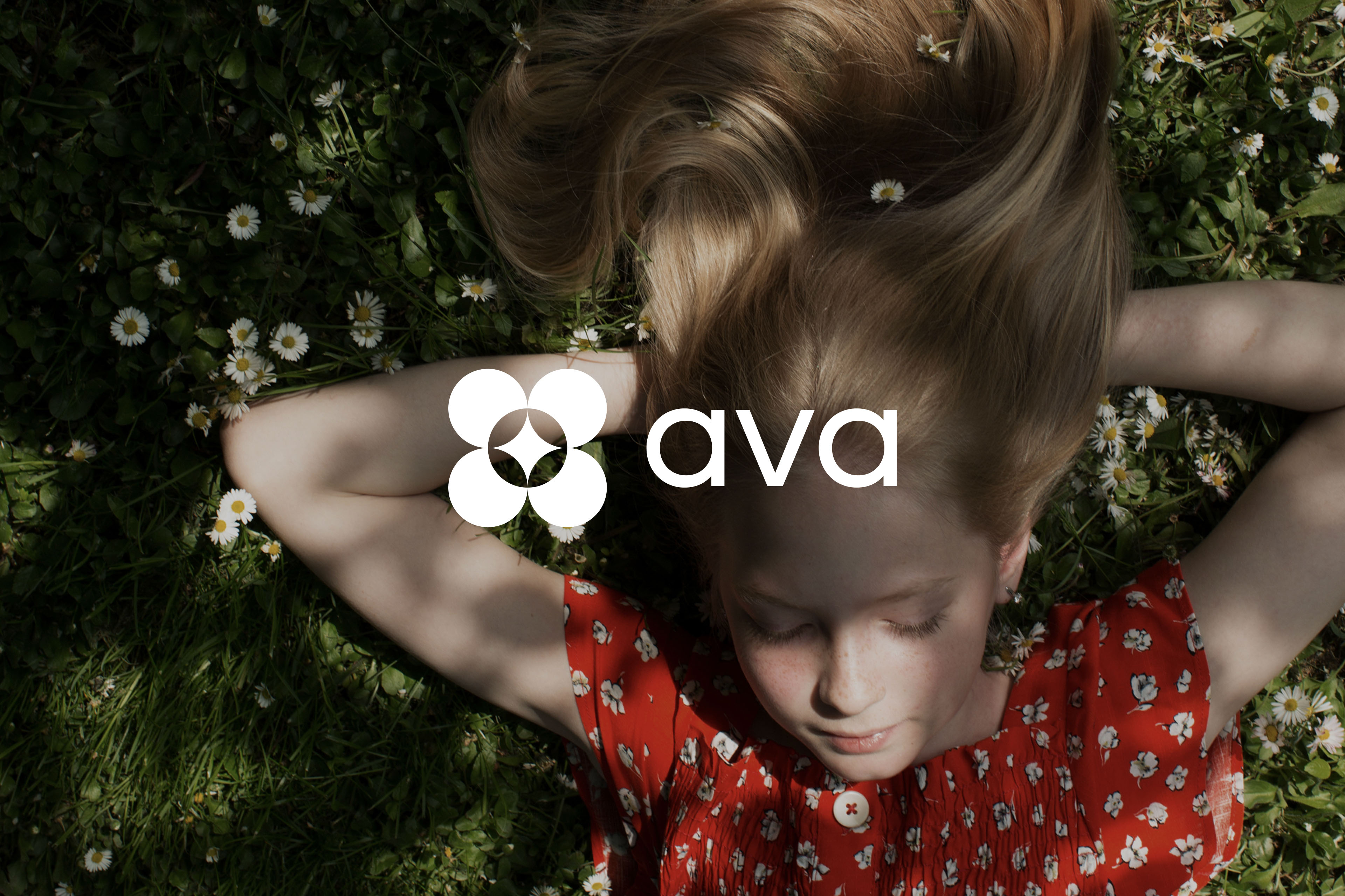 Ava logo overlaid on a photo of a child lying in a field of grass and daisies