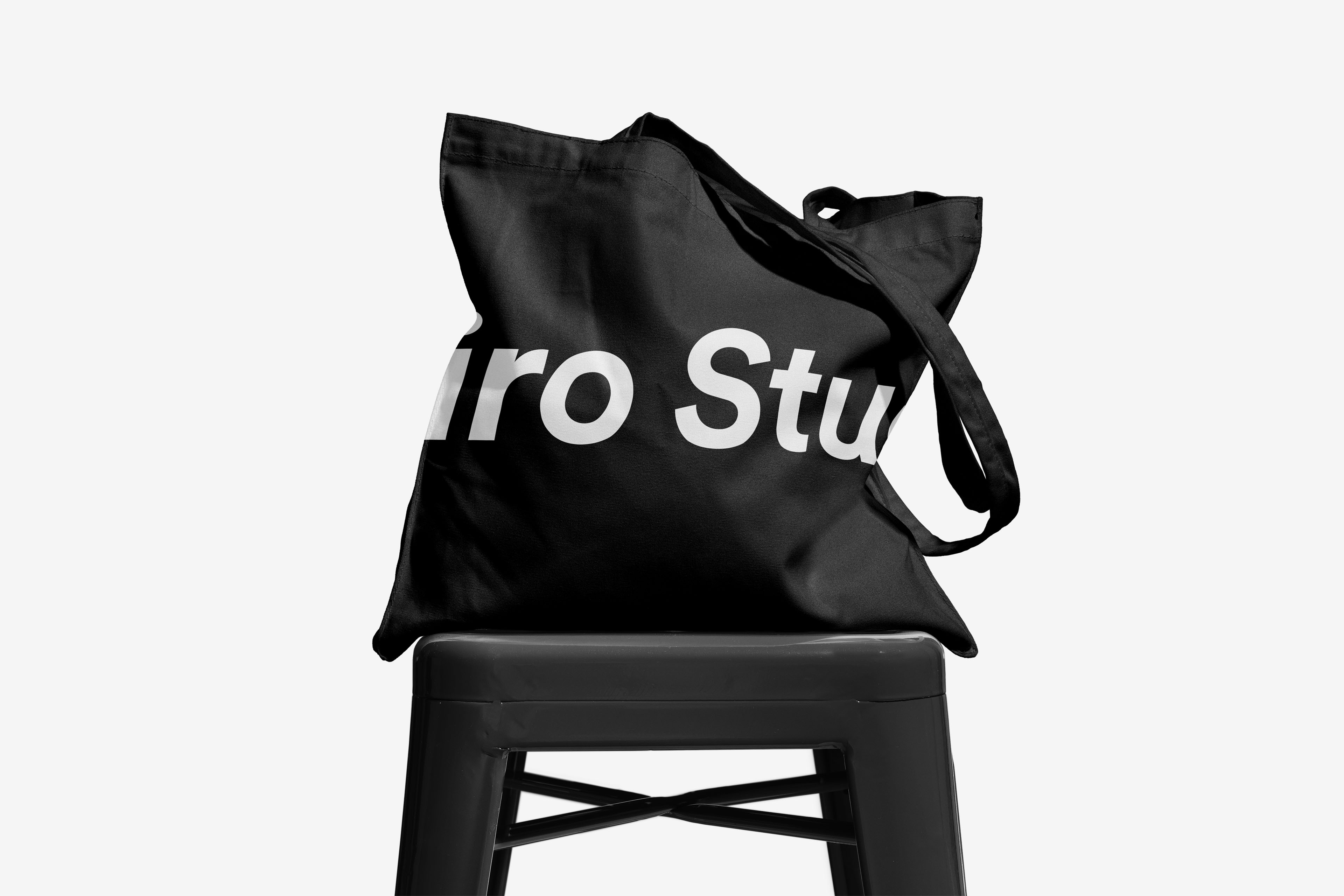 Black tote bag printed with the Noiro Studio wordmark, hung on a stool